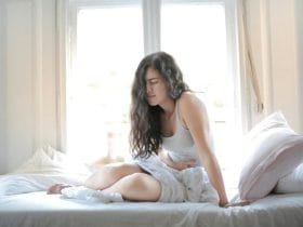 devojka-u-krevetu-stomak-bol