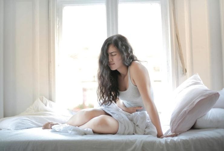 devojka-u-krevetu-stomak-bol